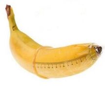 Banane in einem Kondom imitiert einen vergrößerten Schwanz